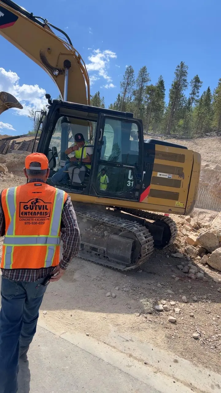 A Gutvil foreman in an orange vest talking with the excavator operator