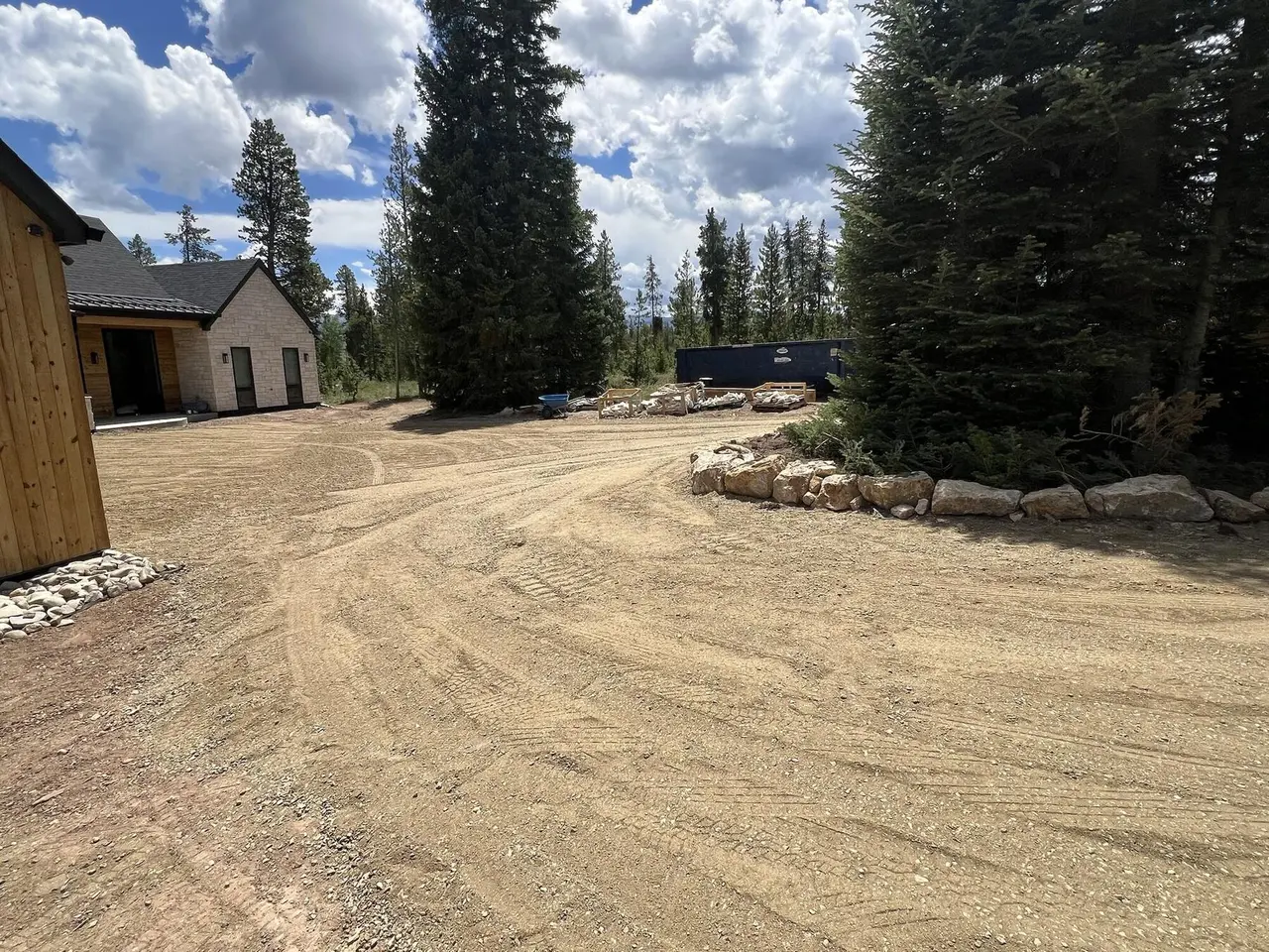 A graded gravel turnaround circling a boulder-ringed spruce tree