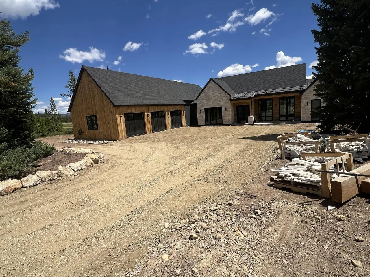A wide graded gravel drive curving to a cedar garage, with boulders along the edge
