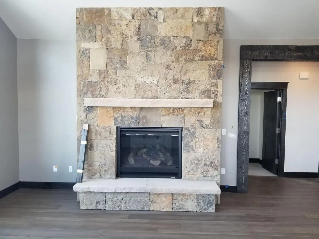 A floor-to-ceiling natural stone fireplace with a stone mantel and hearth