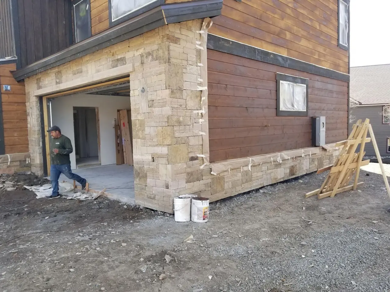 Stacked stone face rock around a garage door and along the base of a house