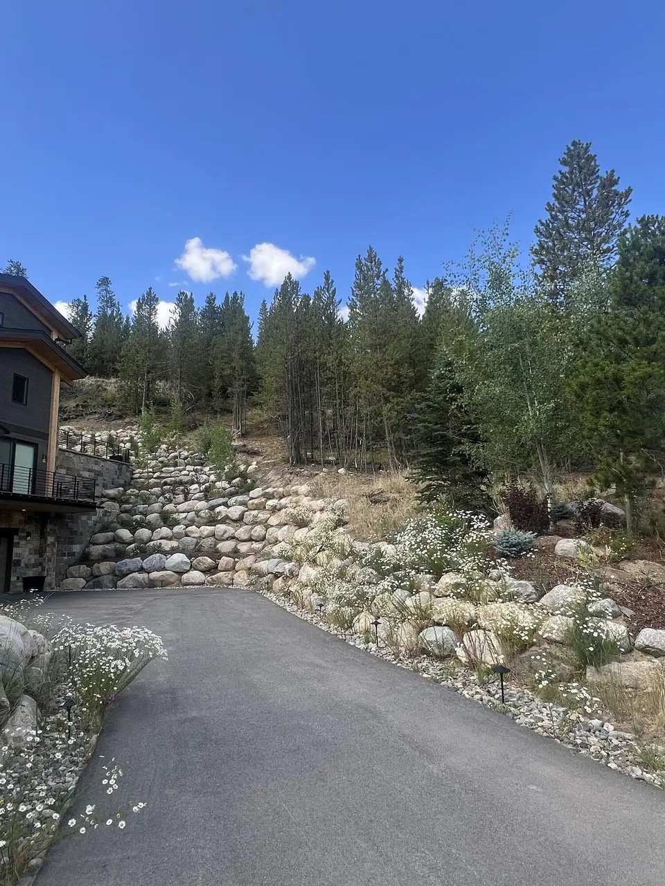 Boulder retaining walls stepping up a slope behind a driveway