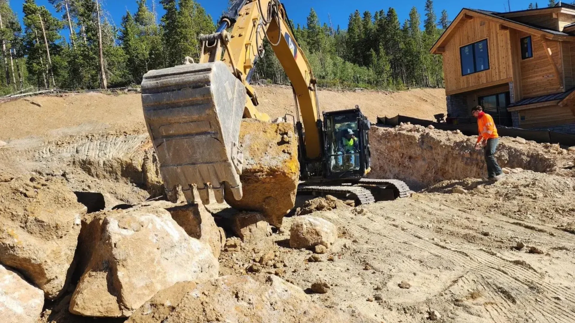 A Gutvil excavator holding a boulder on a mountain job site